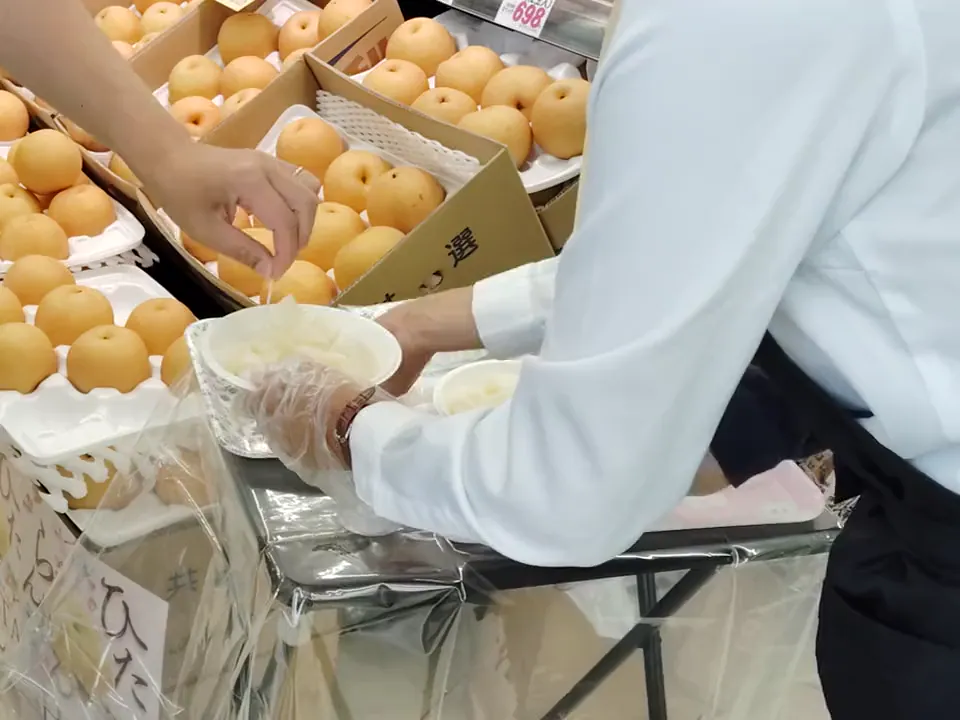 西宮店の農産イベントで梨を試食用に取り分ける様子